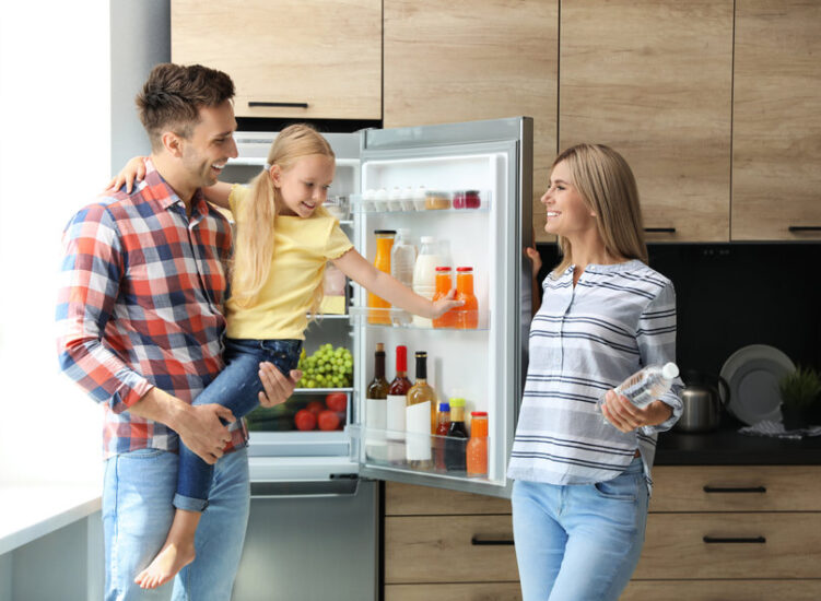 Happy family with bottle of water near refrigerator in kitchen