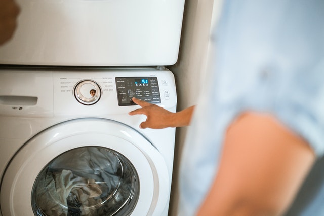 man clicks a button on a washing machine